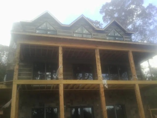 Dormers and porch framing on a large log home under construction — Roof Coating work by our crew in Solon