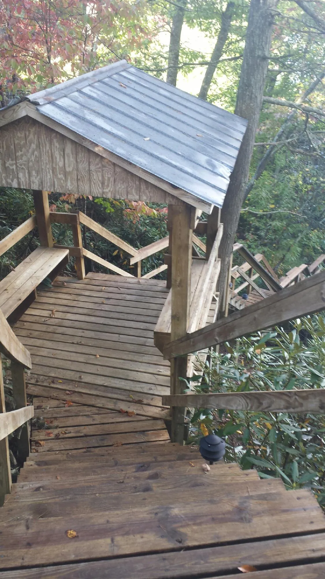 Metal roofed shelter over wooden steps on a wooded walkway — Skylight Repair & Installation work by our crew in Solon