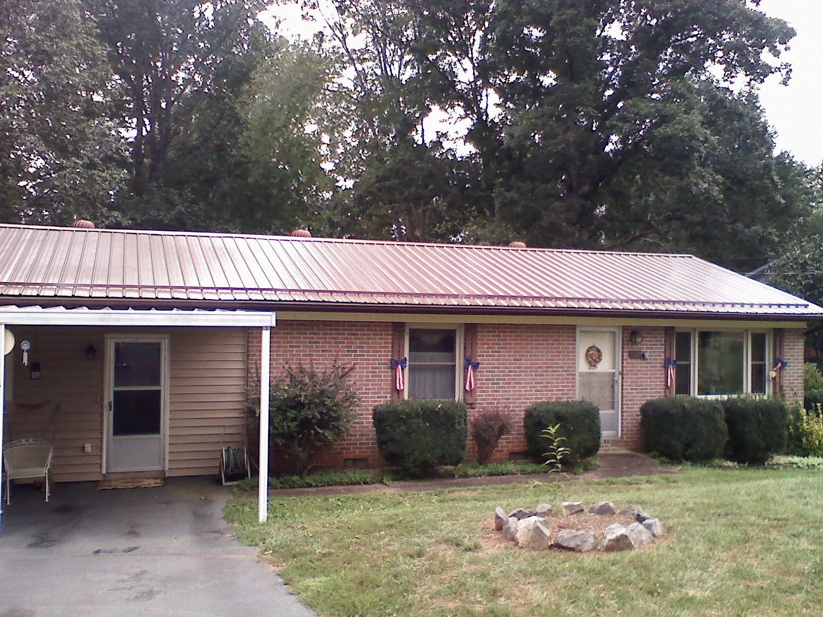 Bronze metal roof and carport on a brick ranch home — Roof Repair work by our crew in Solon