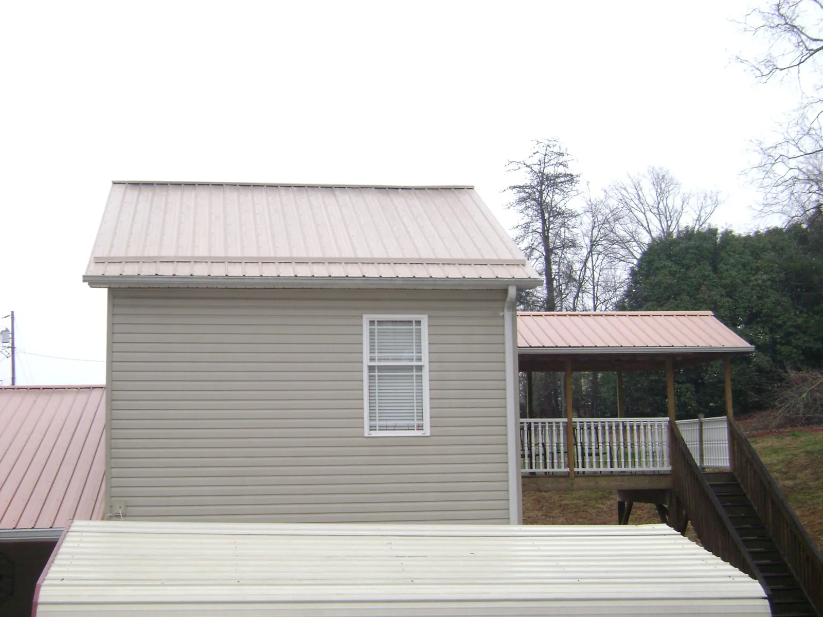 Tan metal roofs on a two story addition and attached porch, from a Roof Replacement job in Solon
