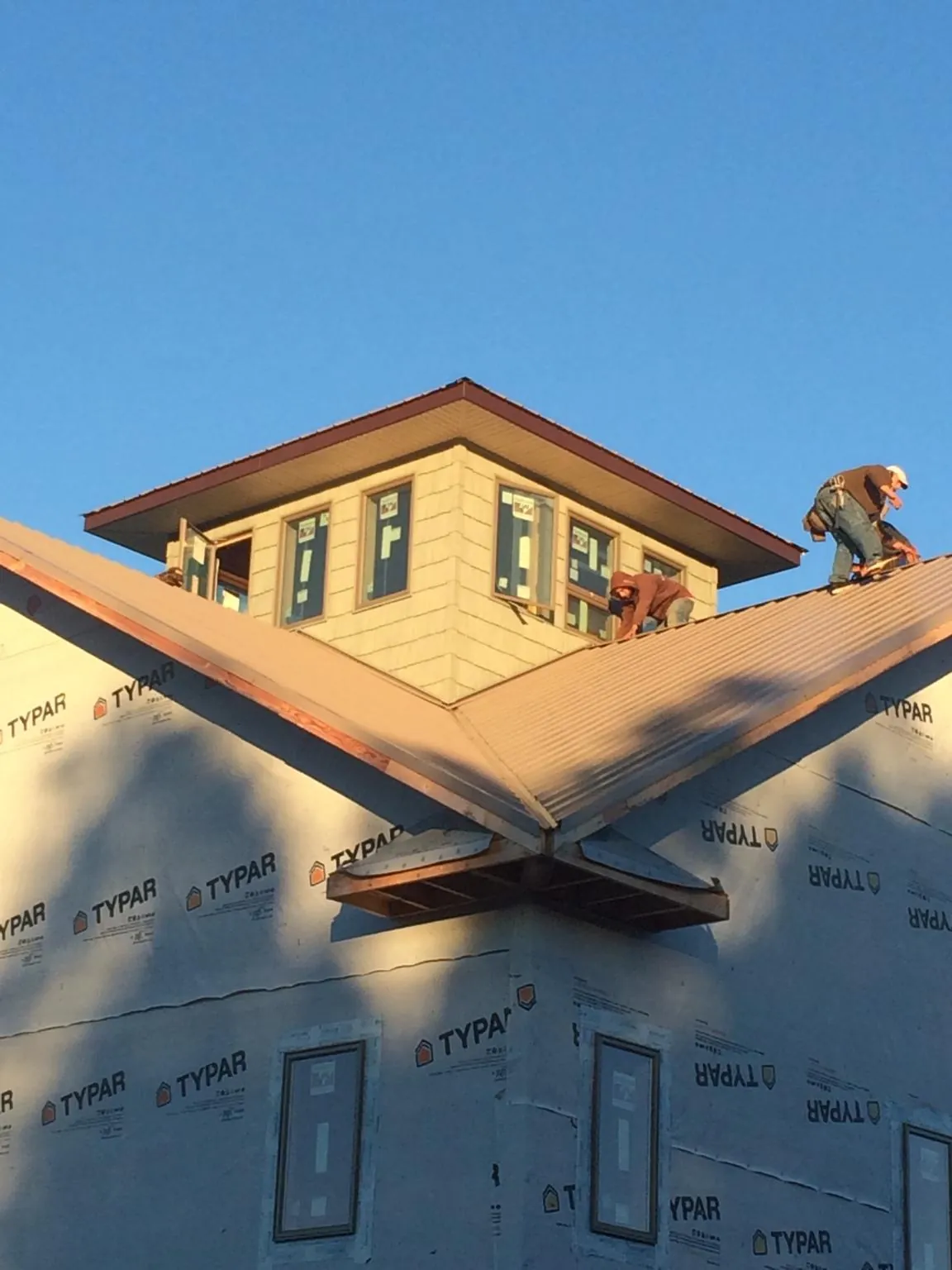 Roofers working around a rooftop cupola on a new metal roof at sunset — Roof Waterproofing in Solon by Roofing Brothers